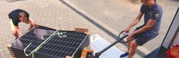 Zwei Menschen laden eine Palette mit Photovoltaik-Anlagen für den Balkon ab